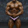 A muscular bodybuilder wearing black and purple MetroMaleWear MetroMuscleWear Mark competition briefs front view