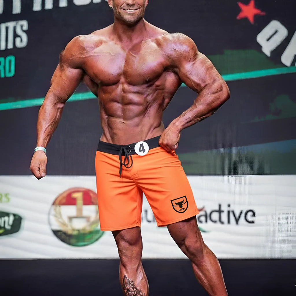 Orange athletic shorts with black waistband and drawstring featuring a small shield logo on the lower right leg