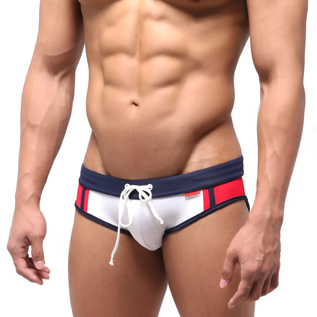 White swim trunks by metromalewear with navy blue and red side stripes and a white drawstring waistband