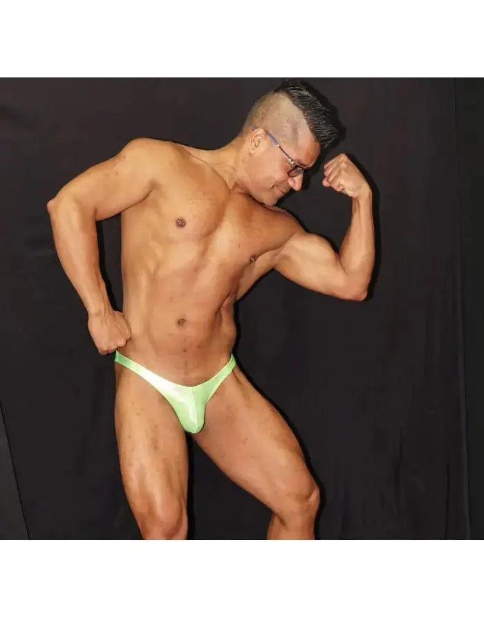 Fluor green micro bikini posing suit by Arroyman featuring a minimal design worn by a muscular model.