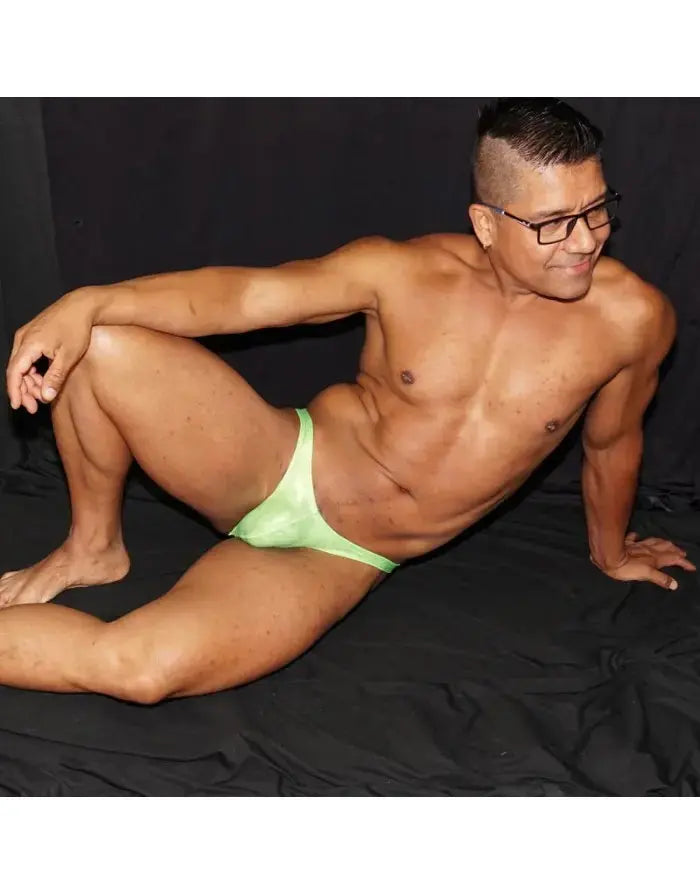 Fluor green micro bikini posing suit by Arroyman featuring a sleek design worn by a model in a relaxed pose.