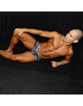 Black leopard print mini boxer underwear by Arroyman shown on a model in a relaxed pose against a dark background.