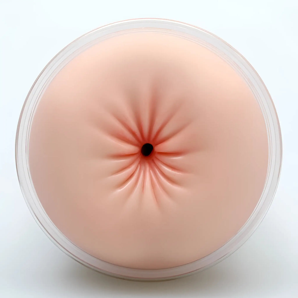A peach-colored silicone anal plug with a black opening and radial indentations in clear plastic for Naked Factory Anna