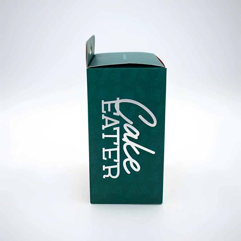 Dark green cardboard box with cake eater printed in white cursive for natalies toy box cake eater clit flicker stimulator pink