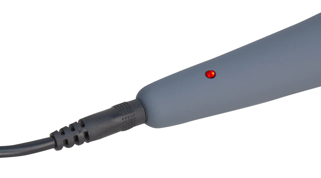 Gray plastic hair straightener with red power indicator light and black cord shown with PalmPower massage wand pink packaging