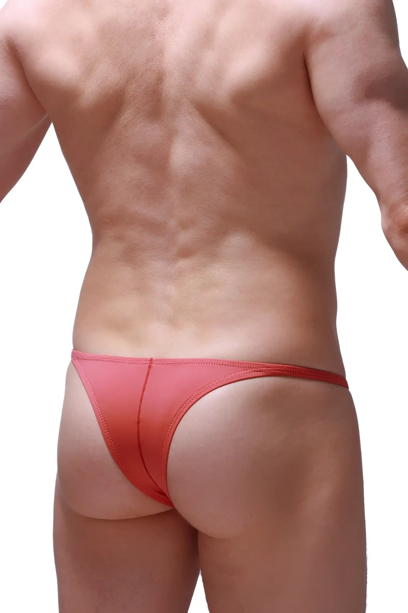 A sleek coral-red petitq bikini plellis blush thong made of smooth stretchy fabric with subtle edge stitching