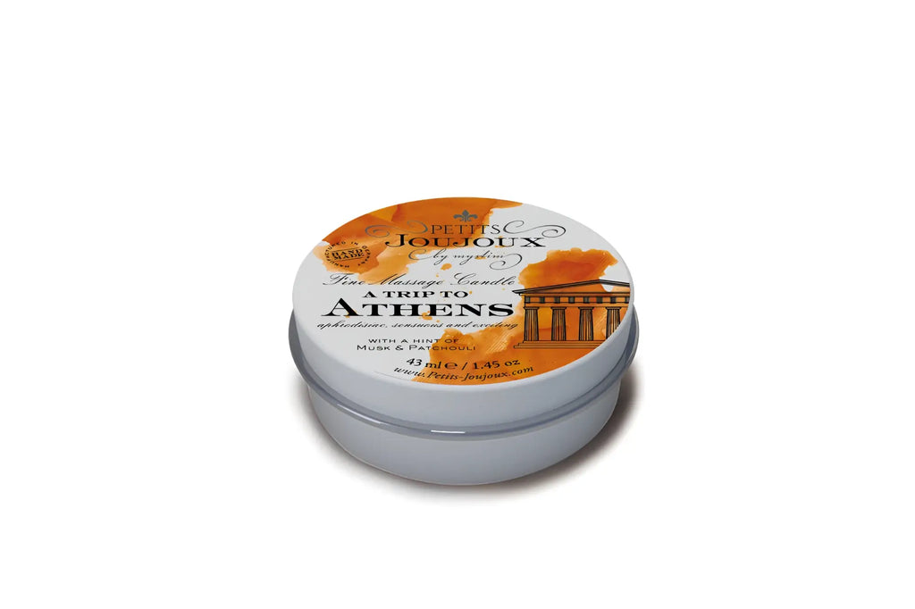 A silver round tin of petits joujoux massage candle with an orange white label scent a trip to athens 43ml