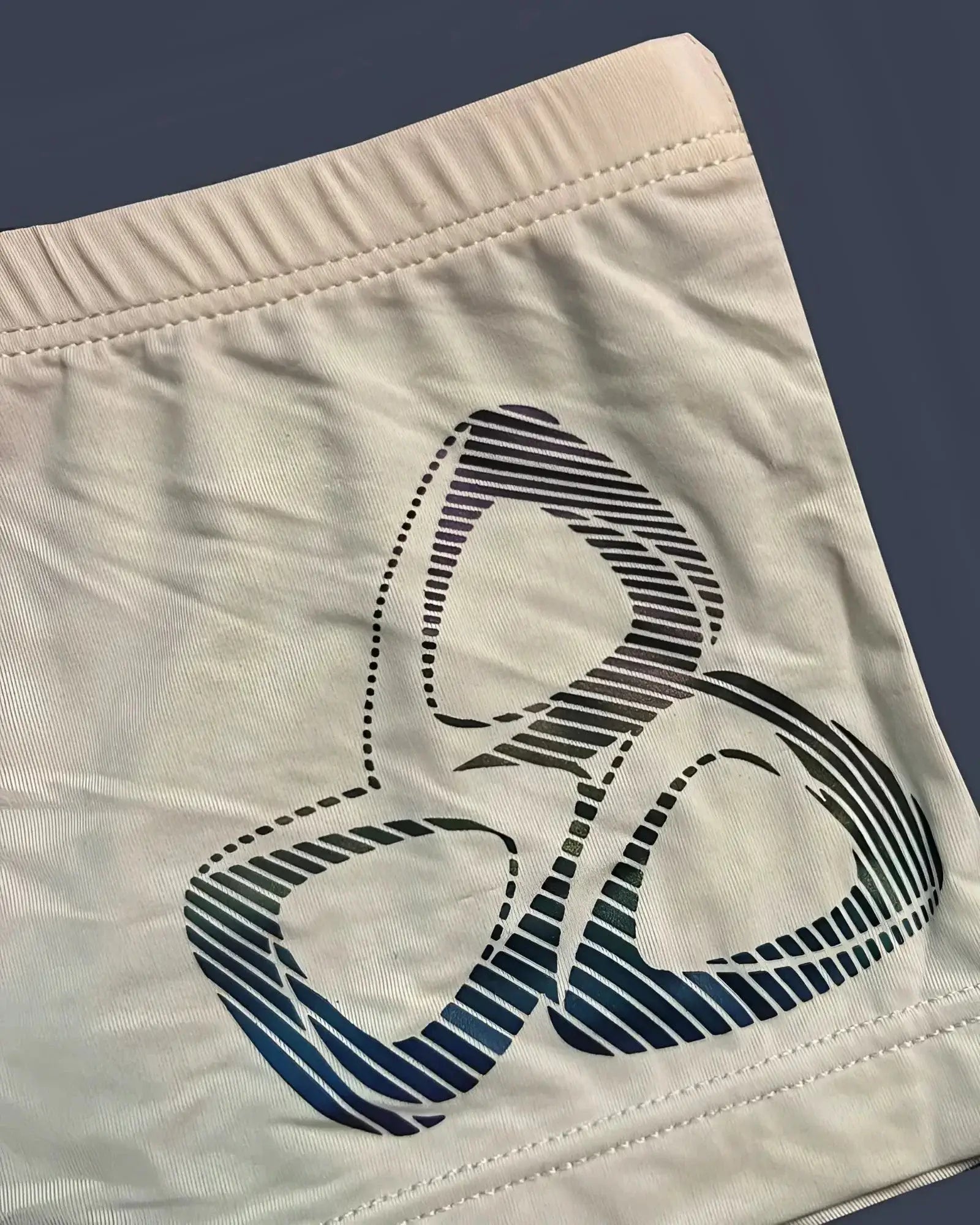 Cream-colored Private Structure BRUT4390 bare hipster shorts with bold blue and black gradient biohazard symbol print