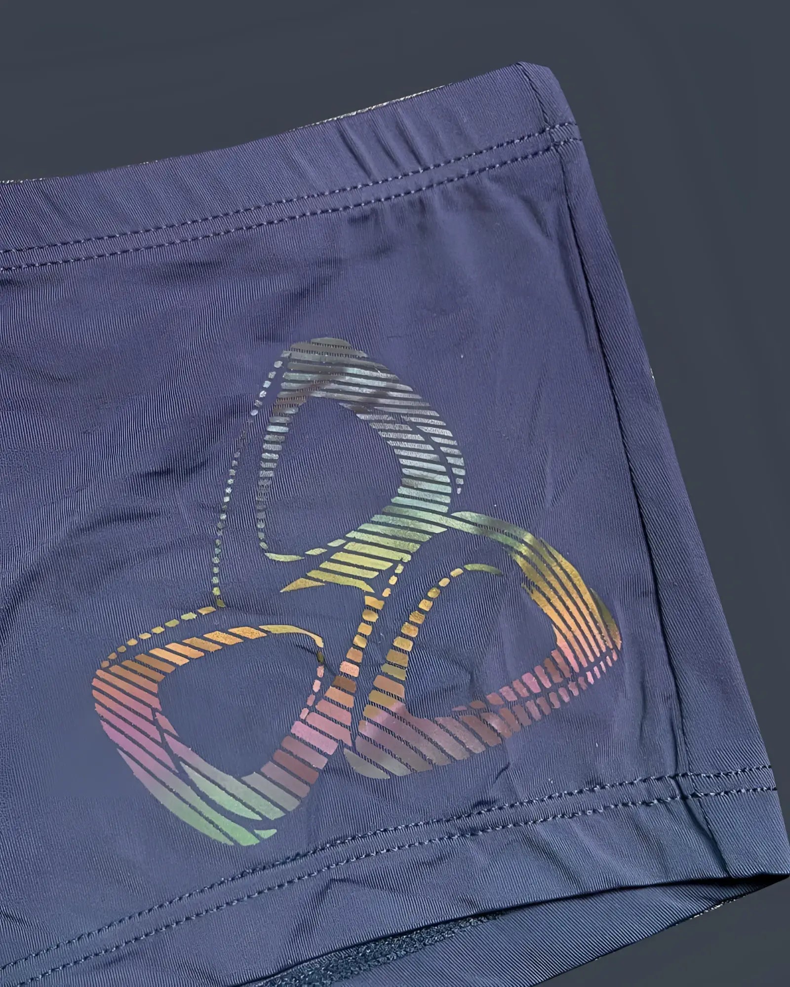 Dark blue silk athletic shorts by private structure with a vibrant rainbow-striped abstract logo on the fabric