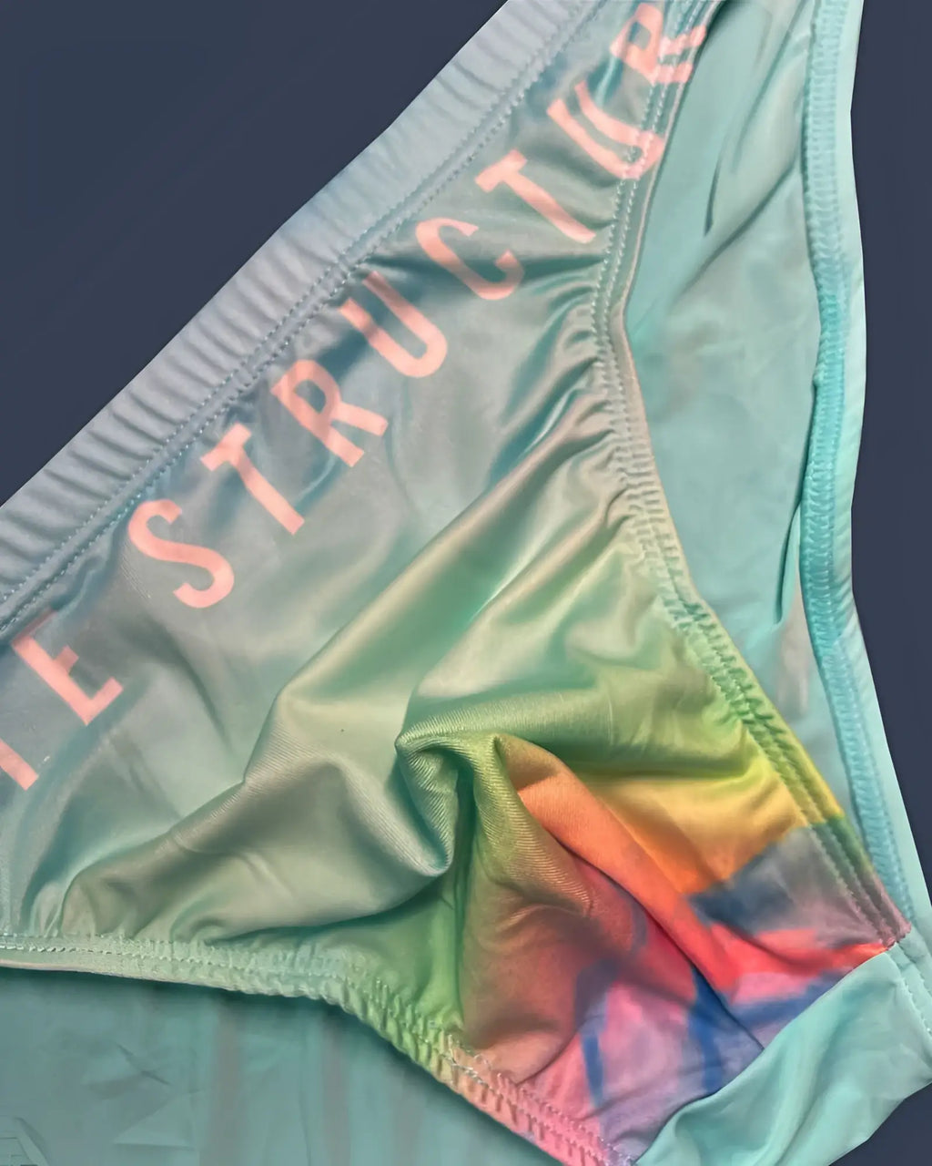 Pastel green tie dye bikini bottom by private structure with instructor printed in pink on cyan mist waistband