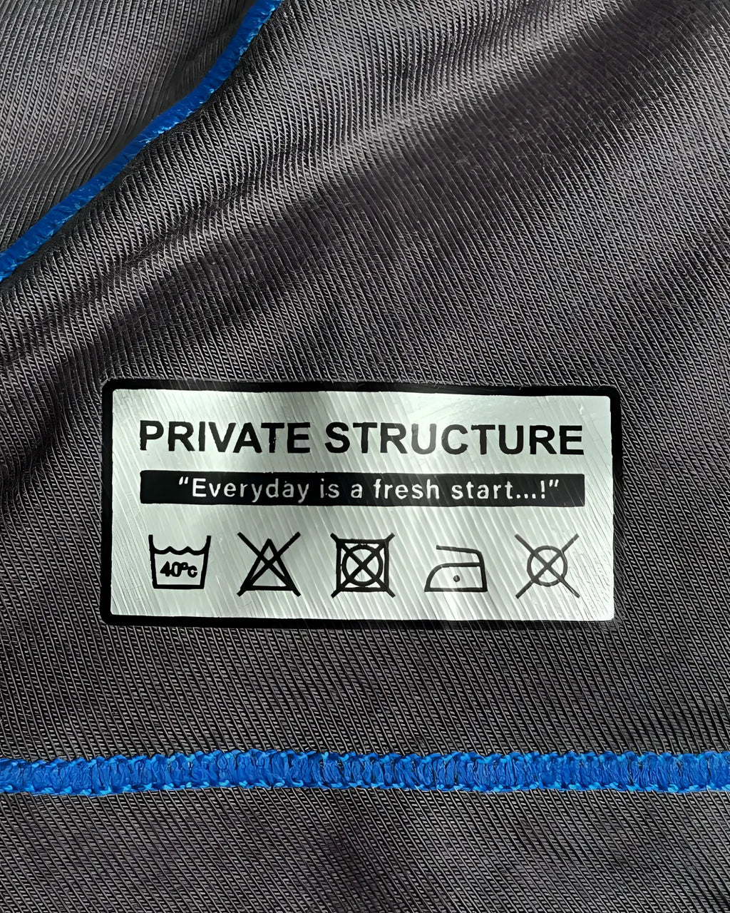 Gray fabric with blue stitching and white private structure care label on the back of epus4570 prime elysian hipster