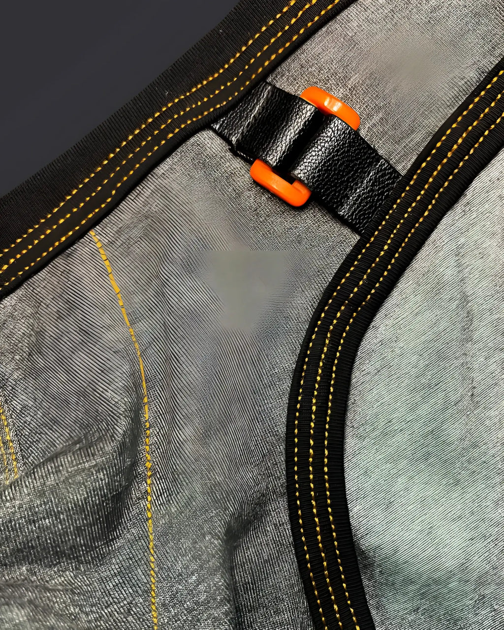 Black leather strap with bright orange plastic buckle stitched on gray textured fabric of private structure barn boy mini brief