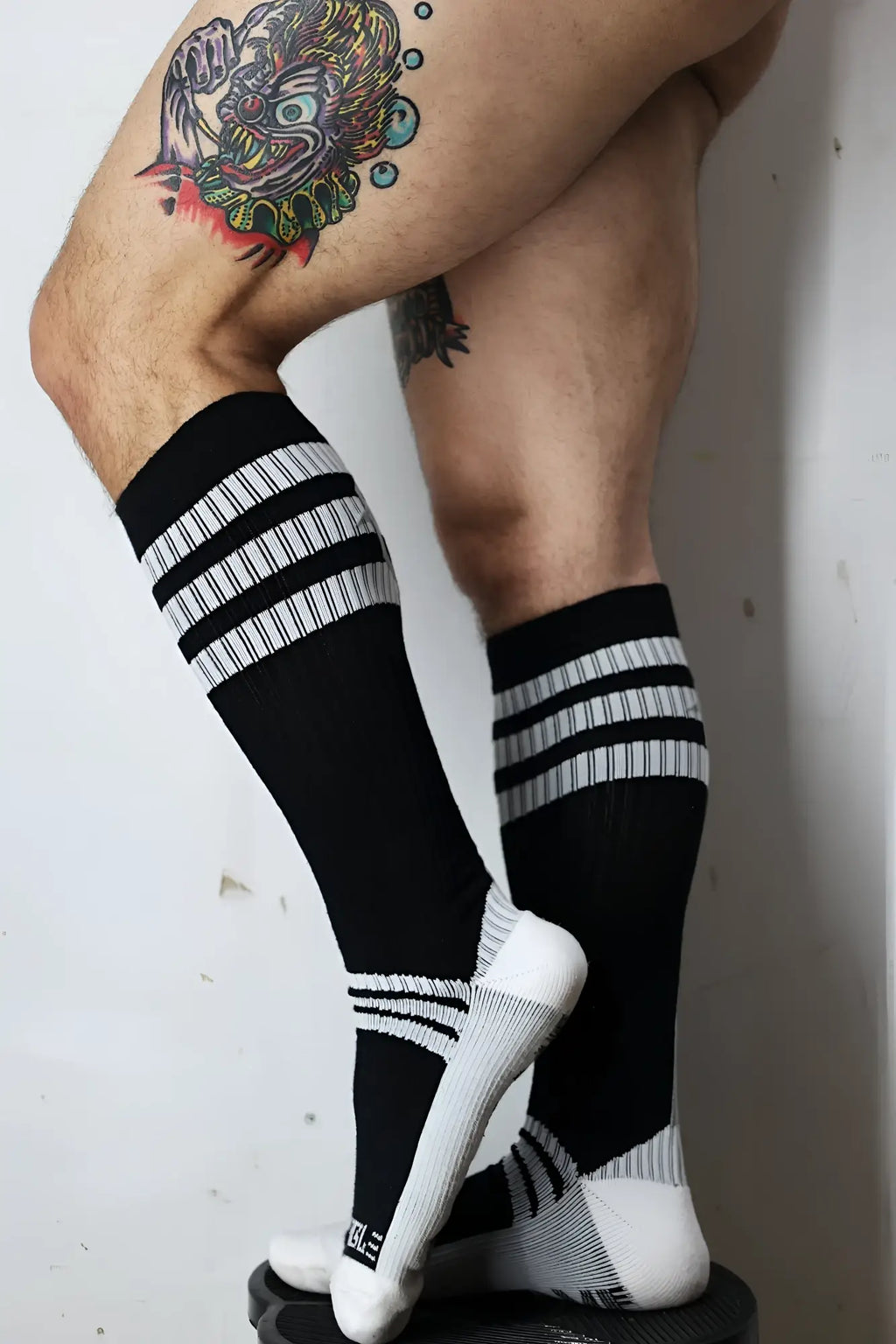 Black retro remix athletic socks with three white stripes textured foot pattern and small heel logo shown from back
