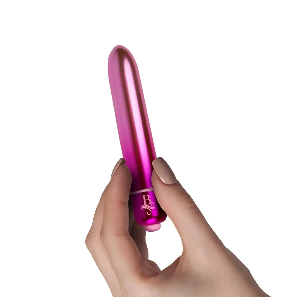 A sleek metallic pink cylindrical vibrator with a glossy finish and engraved logo rocks off boudoir courtesan bullet