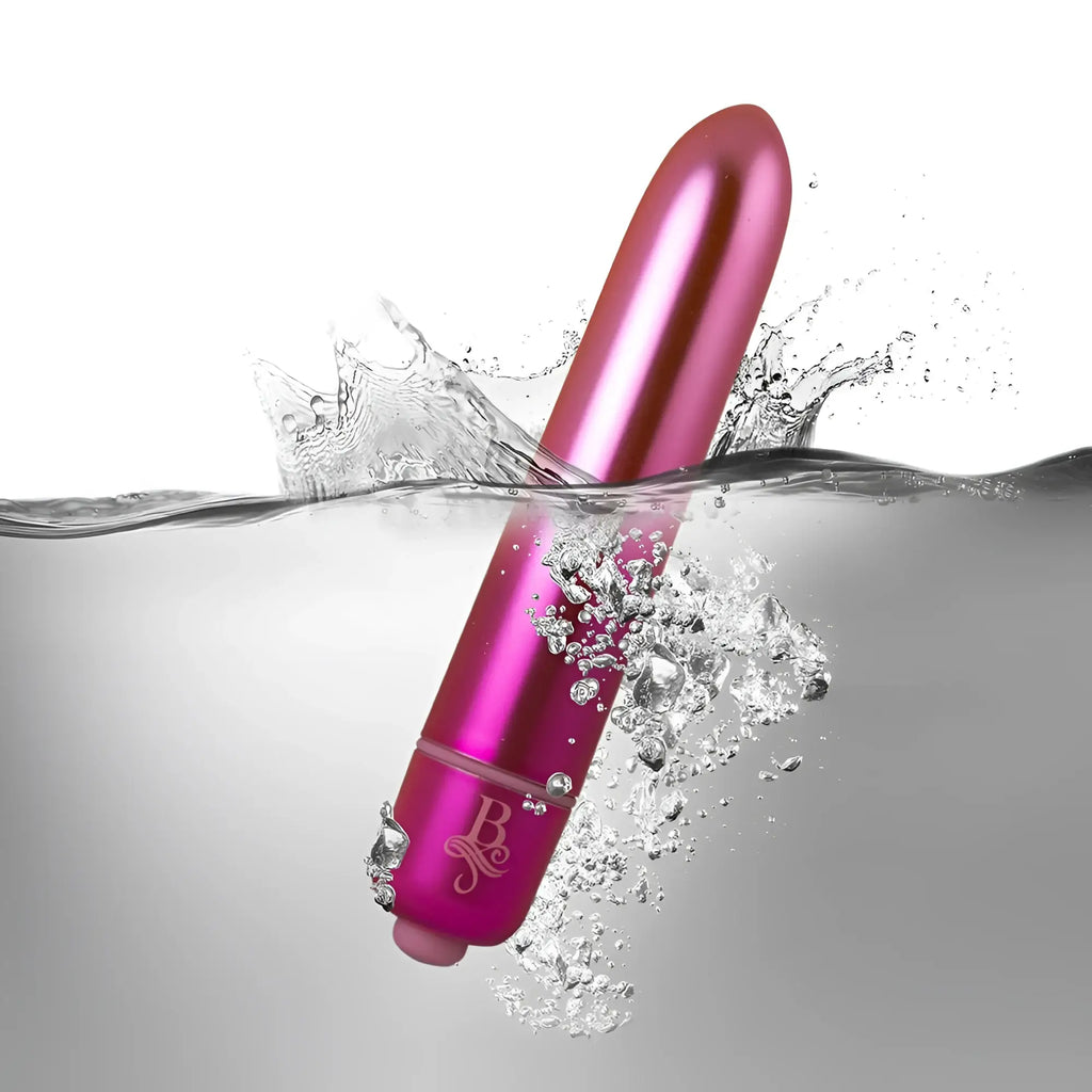 A sleek metallic pink cylindrical vibrator with glossy finish and engraved logo near the base rocks off boudoir courtesan bullet