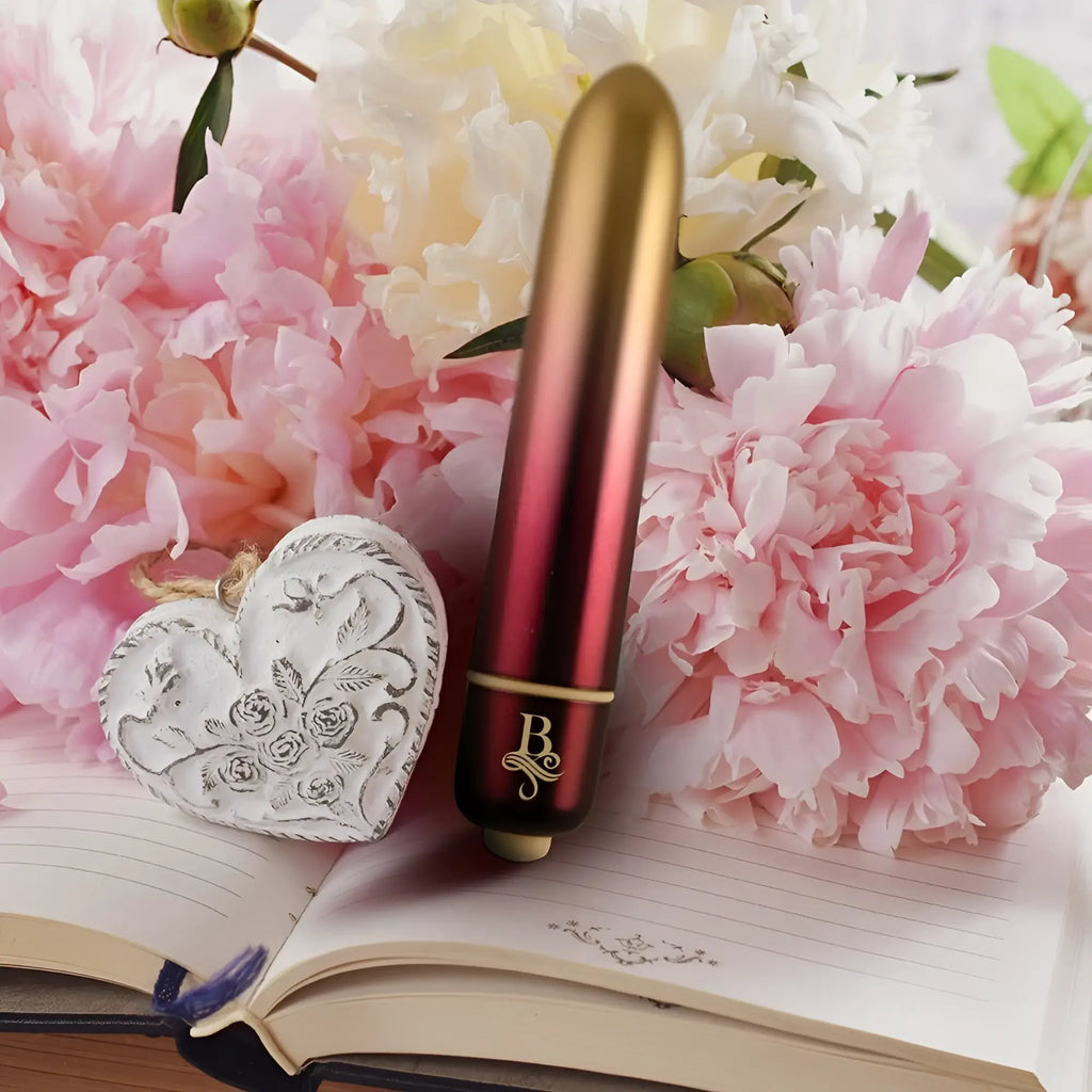A sleek red to gold cylindrical vibrator with a gold accented base and elegant b logo rocks off boudoir debutante bullet