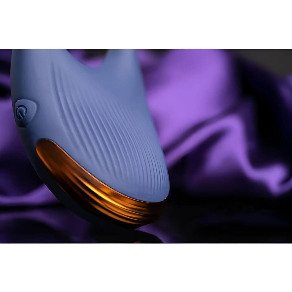 A sleek matte lavender whale shaped Rocks Off Climaximum vibrating cock ring with a glossy gold underbelly and ribbed texture