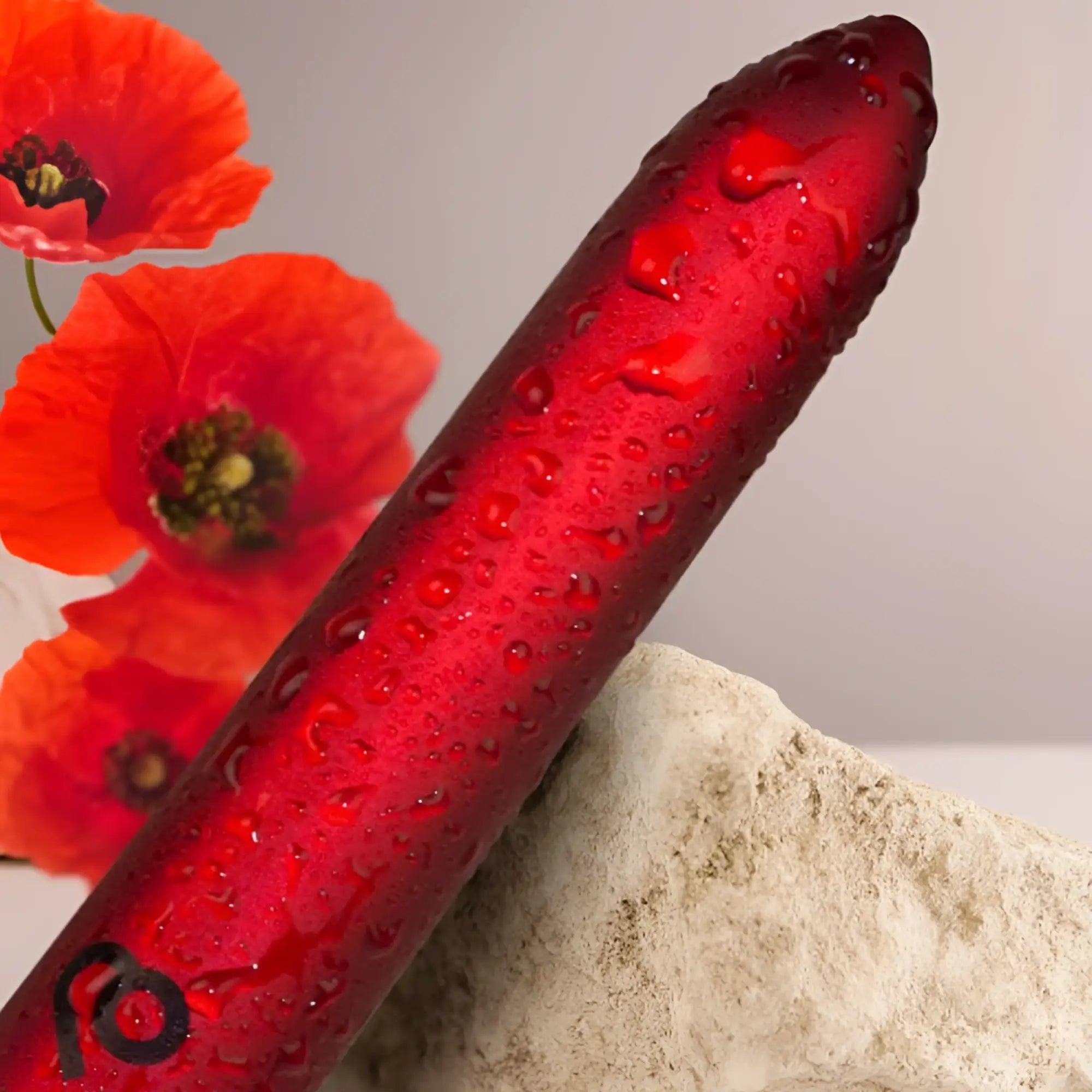 A glossy red rocks off poppy rechargeable bullet with water droplets and a black logo near the base