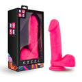 Bright pink silicone dildo from ruse displayed beside its black and colorful packaging for adult use