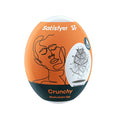 Orange and black satisfyer masturbator egg crunchy with white top cap and illustrated face design on the side