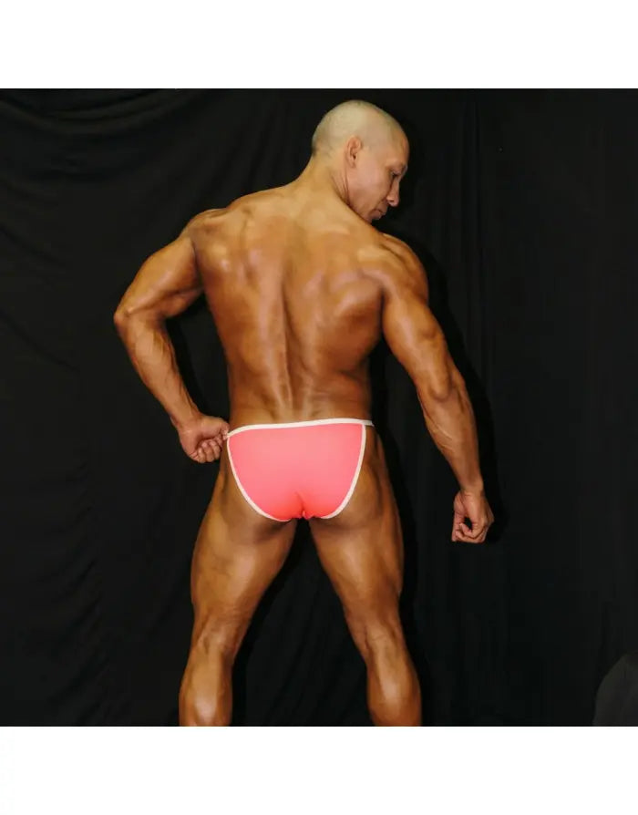 Neon pink men's bikini underwear with white trim shown on a model from the back by Arroyman.