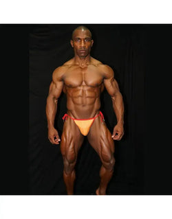 Arroyman men's sling bikini in orange and red featuring a minimal design and adjustable side ties modeled by a muscular man.