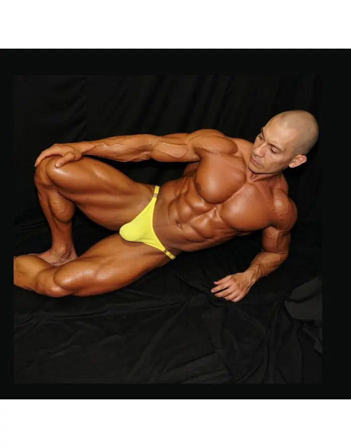 Model wearing yellow thong underwear by Arroyman showcasing a snug fit and minimal coverage against a dark background.