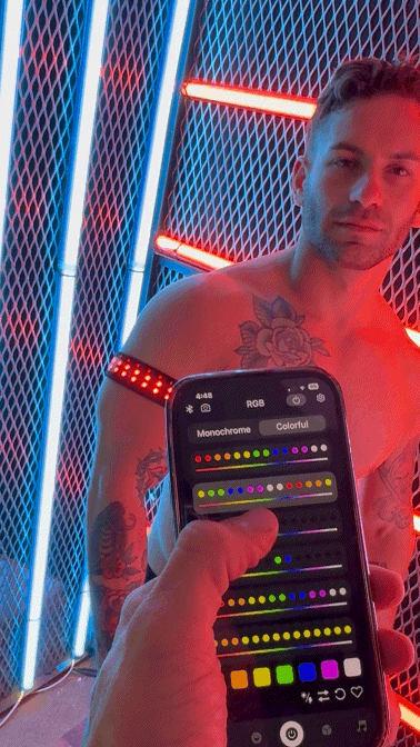 A sleek black smartphone displaying a color picker held by a man wearing illuminated Soundwave armband with led lights