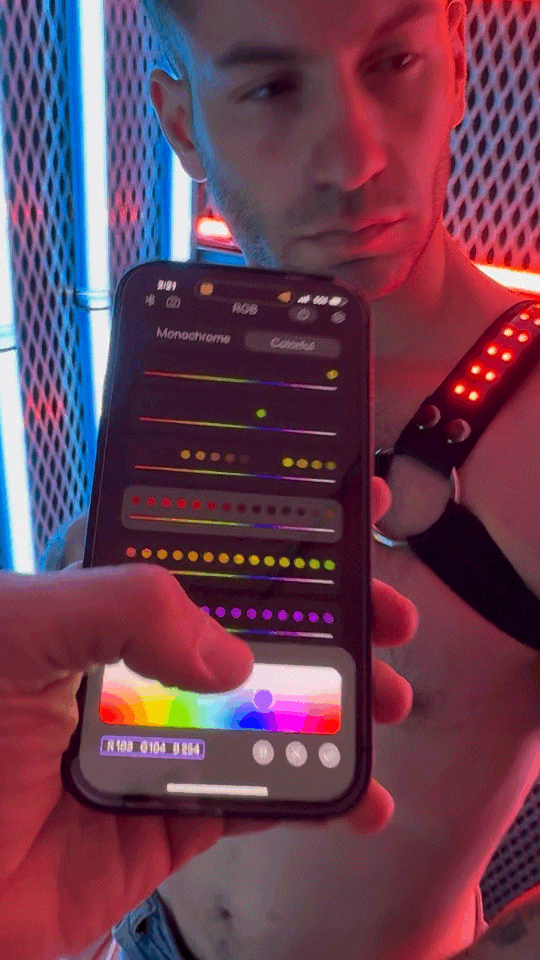 A black smartphone held in hand showing a color adjustment interface with sliders for monochrome and colorful modes