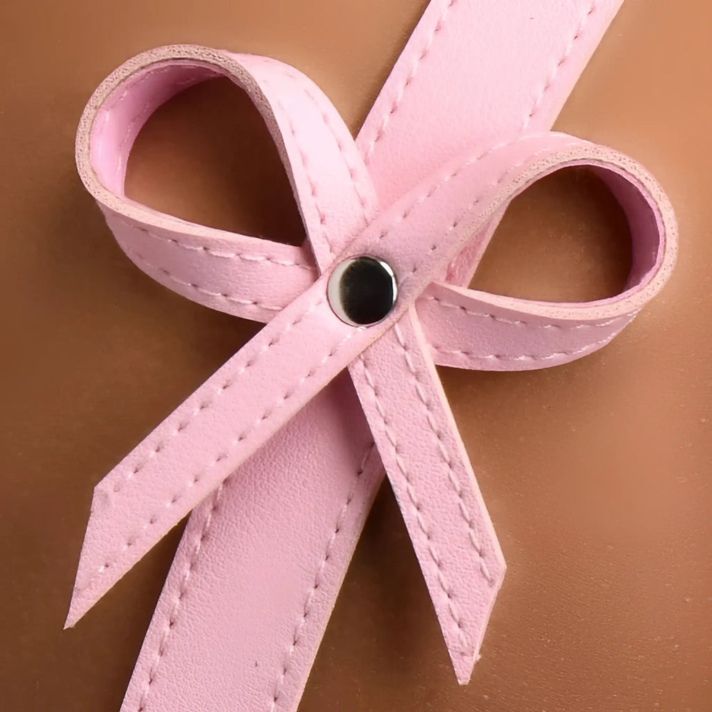 Pink leather strict bondage harness with white stitched ribbon bow and silver button at the center in size m/l
