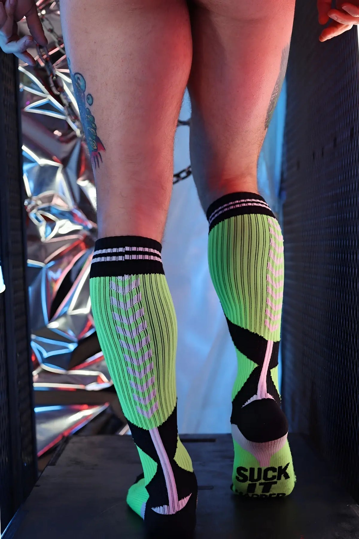 Neon green and black athletic socks with pink accents showing bold suck it graphic on the back heel