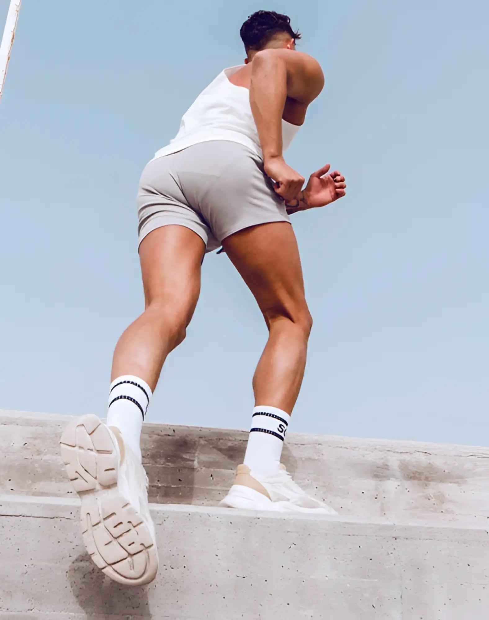 White and beige chunky sole athletic sneakers paired with black striped socks and grey white supawear jersey shorts