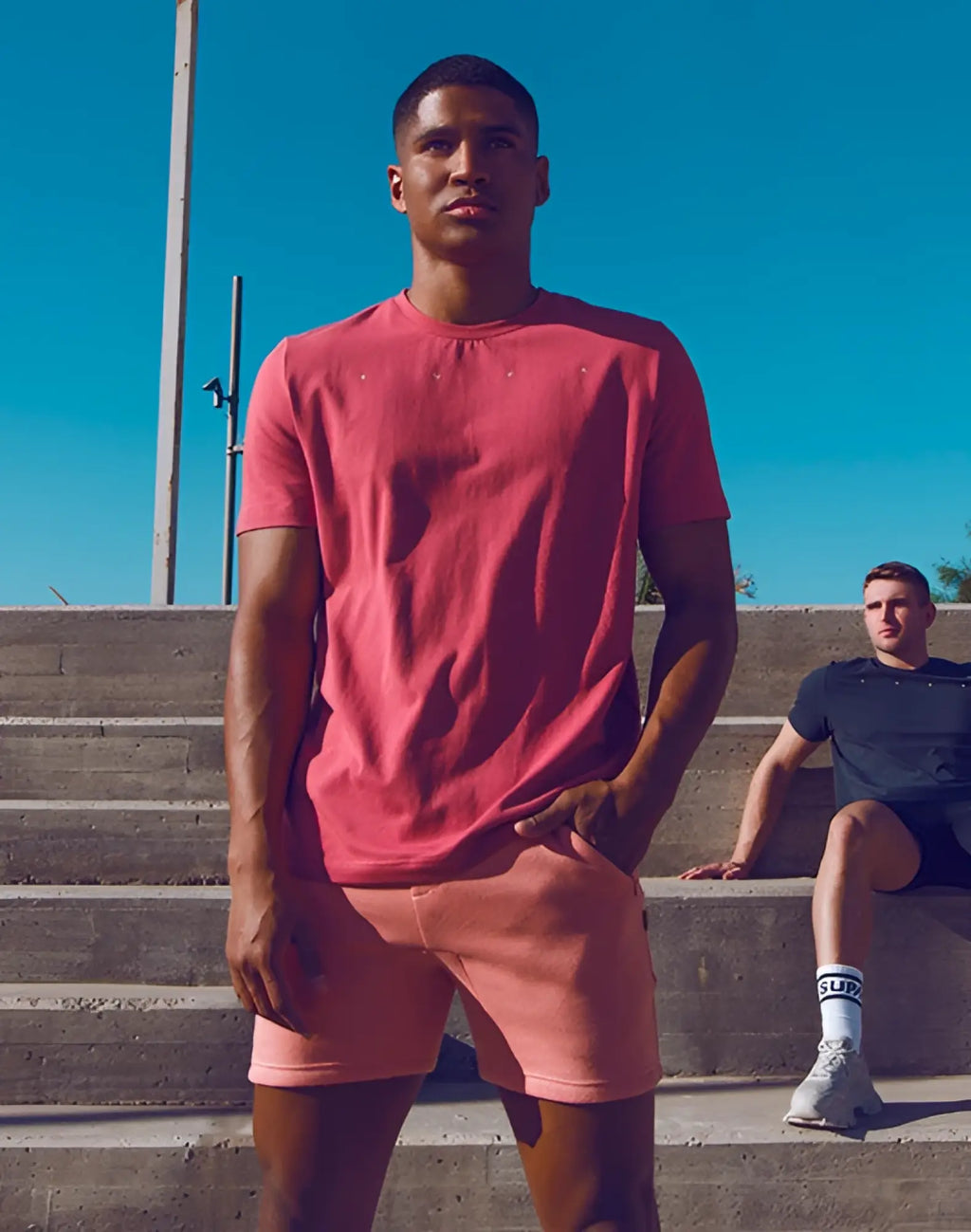 A man wearing a SUPAWEAR classic short sleeve cotton t-shirt in coral with subtle embroidered details