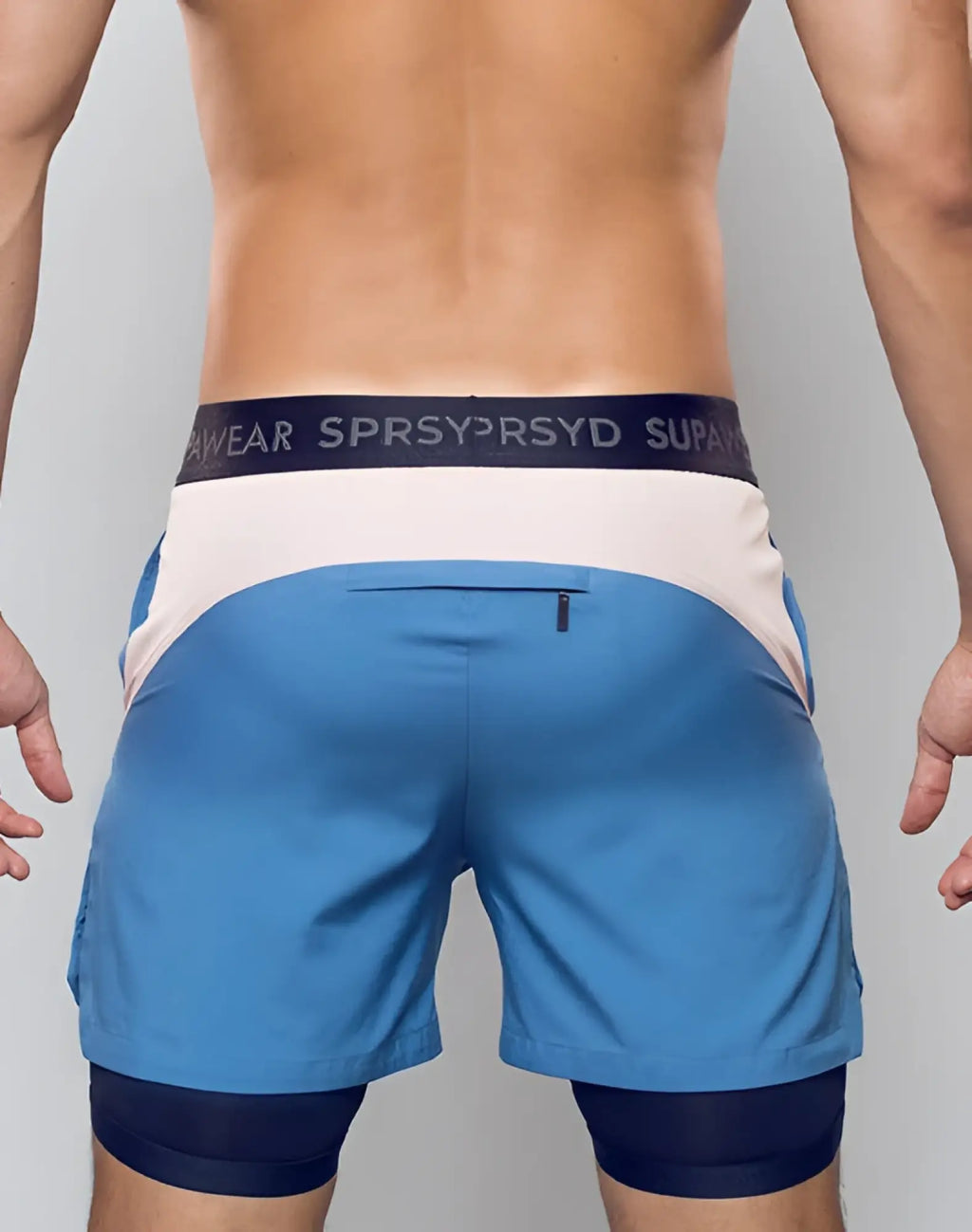 Blue supawear colour blocked lined athletic shorts with white and navy waistband layered over dark blue compression shorts