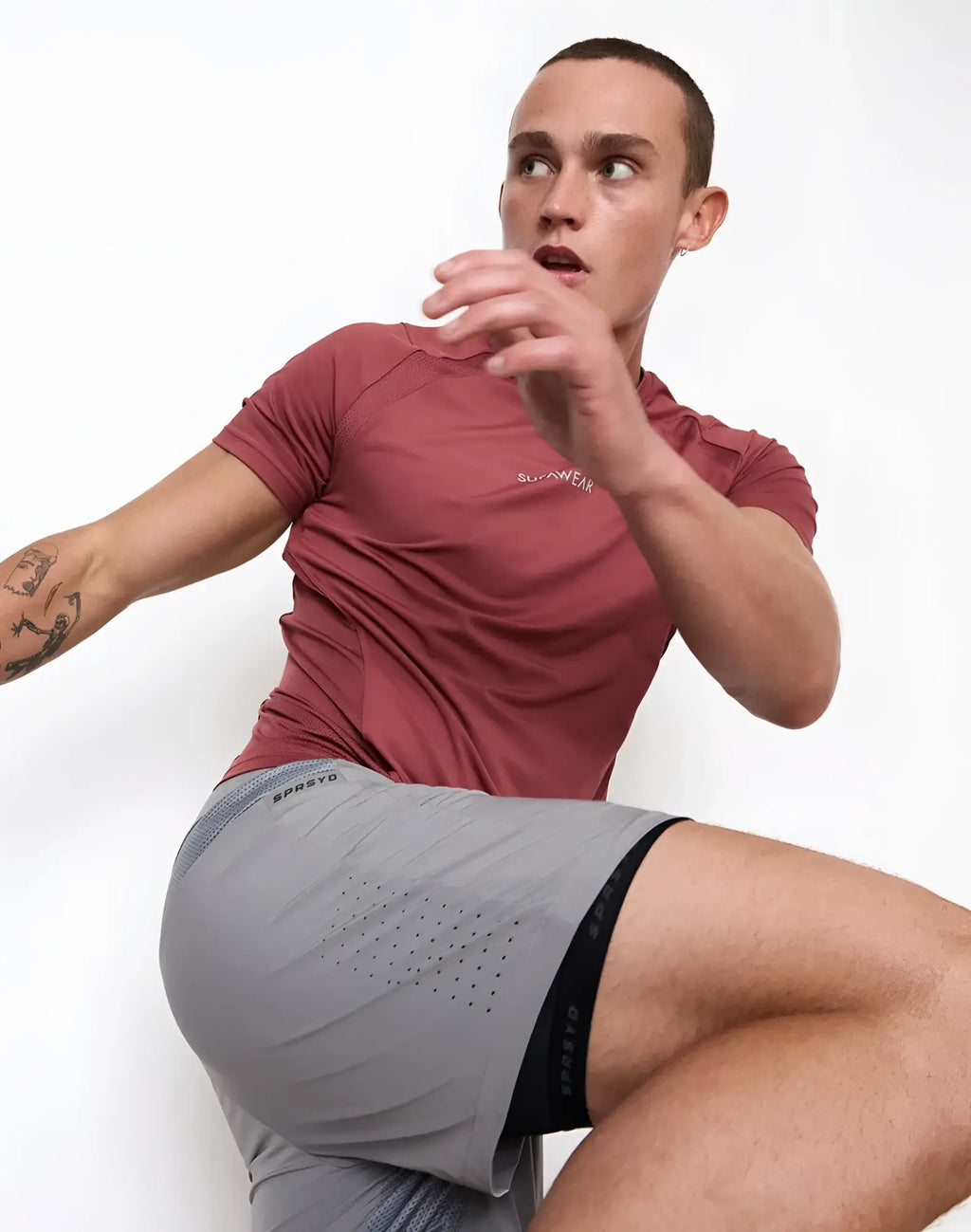 Gray athletic shorts with black elastic waistband and perforated side panels paired with supawear contouring red t-shirt