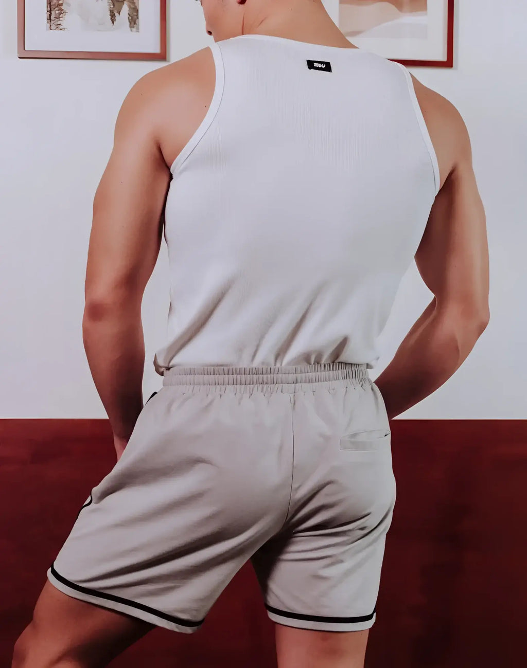 Back view of white ribbed tank top with black brand tag paired with supawear crux grey shorts