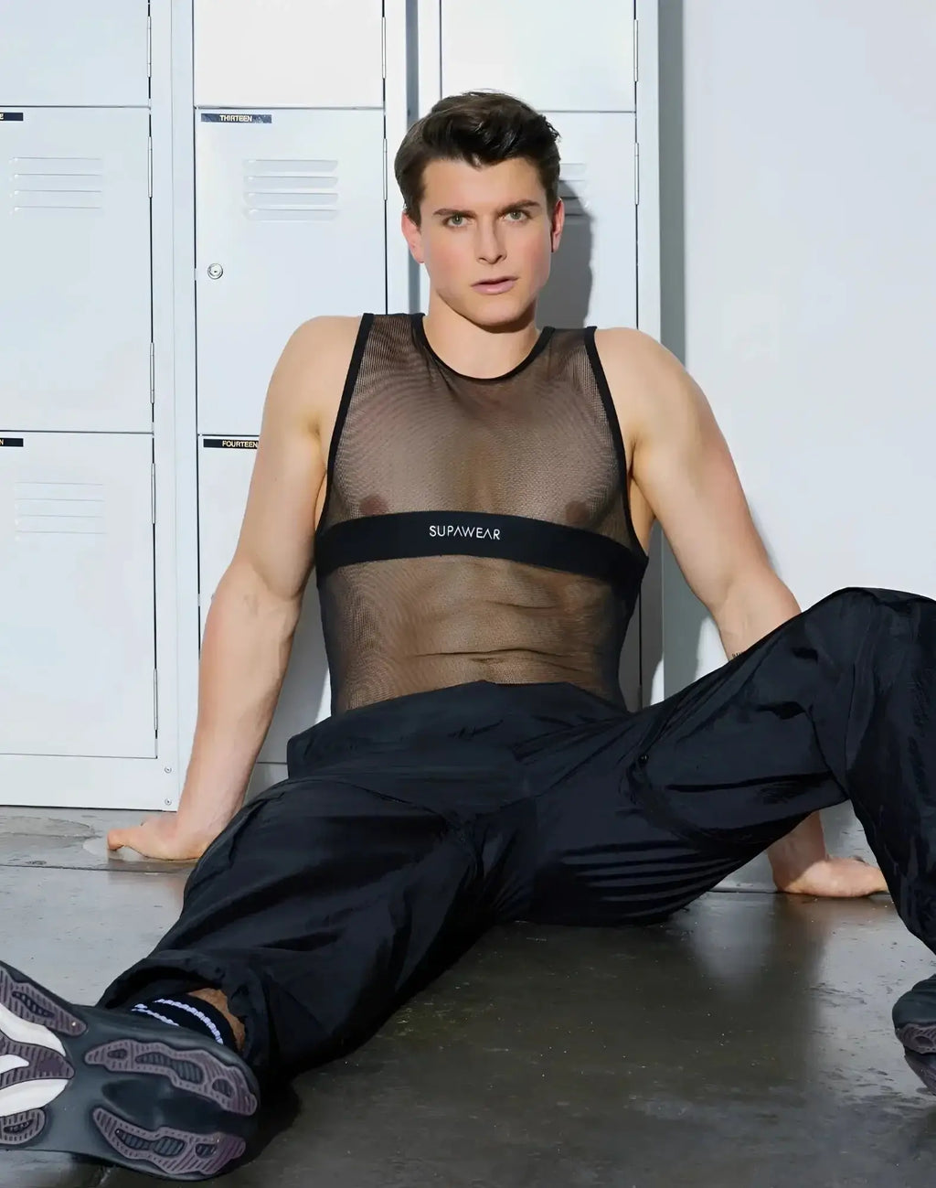 Black mesh tank top with a black chest band featuring white supawear lettering and breathable fabric