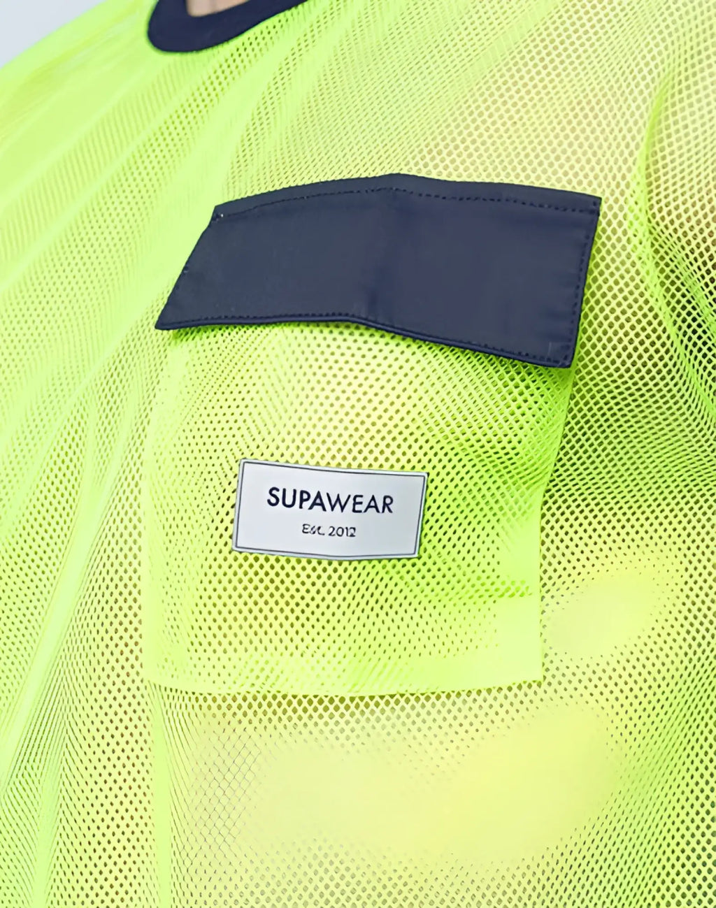 SupaWear neon green mesh top with dark navy fabric patch and white label est designed for stylish breathability