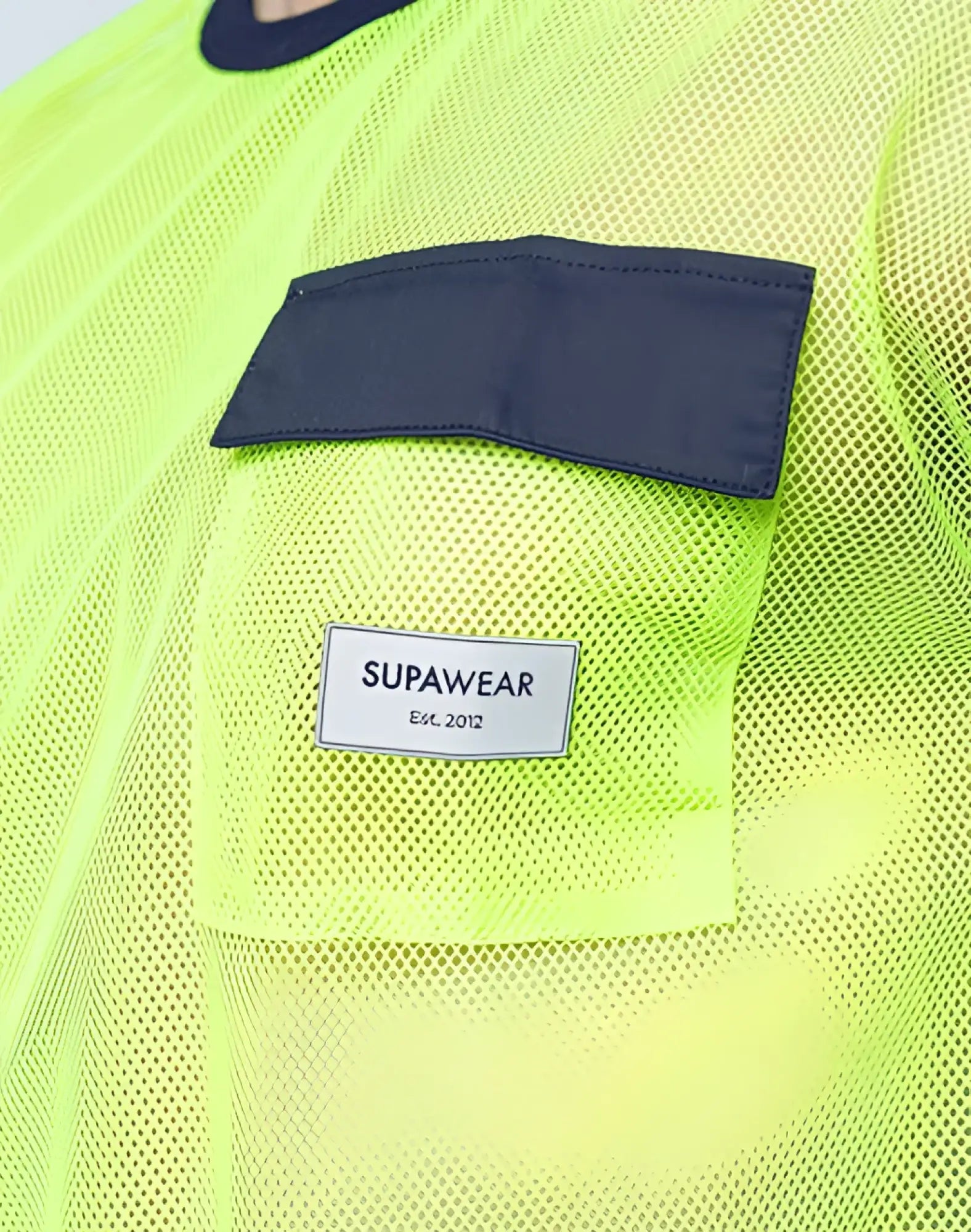 SupaWear neon green mesh top with dark navy fabric patch and white label est designed for stylish breathability