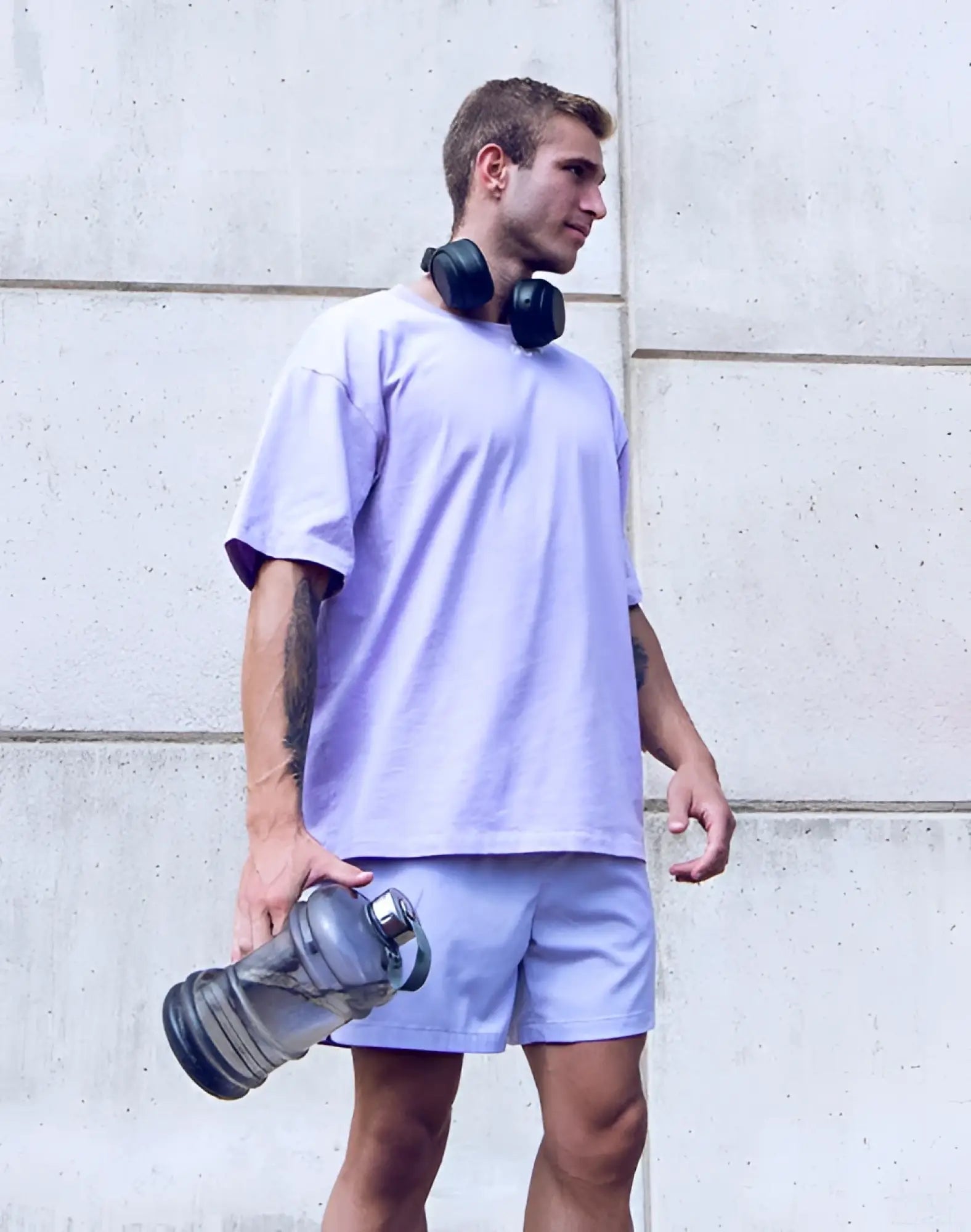 A translucent gray water bottle with metallic silver lid and textured grip shown with supawear oversized tee purple heather