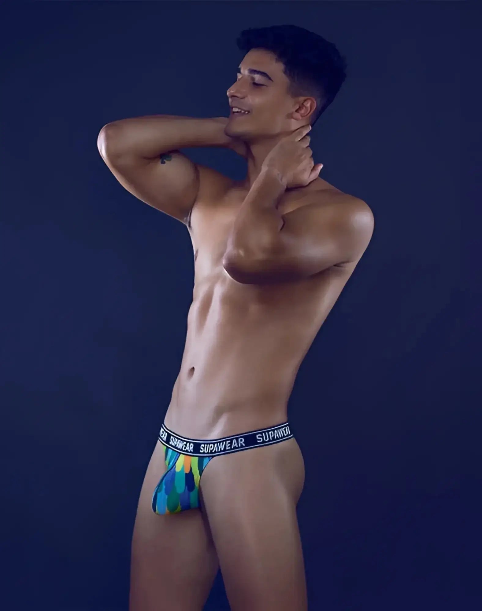 SupaWear POW thong underwear with vibrant multicolored peacock feather pattern and black waistband with white lettering