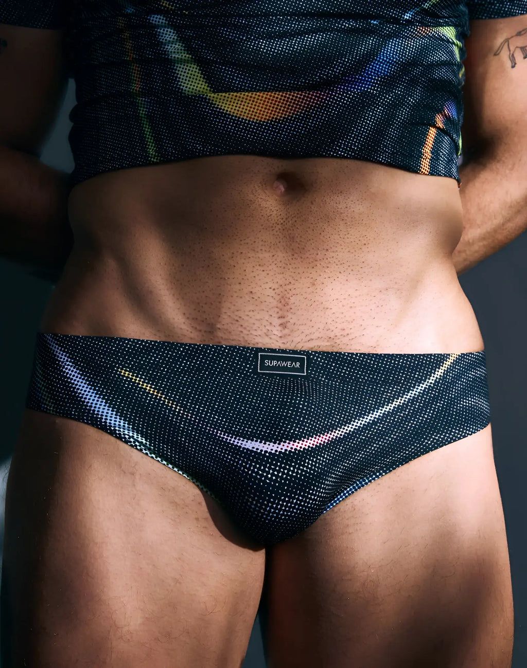 Black mesh SUPAWEAR printed pride brief underwear with subtle iridescent sheen and diagonal rainbow stripes