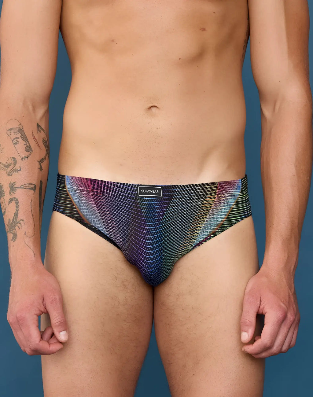 A men’s brief with vibrant iridescent purple blue and green geometric pattern and sunwear label on waistband