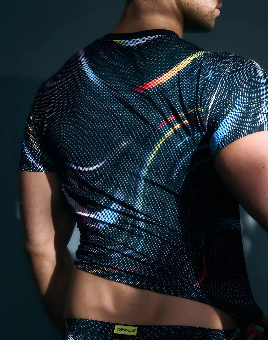Black short-sleeved SUPAWEAR printed pride crop t-shirt with vibrant rainbow light streak pattern and dot texture