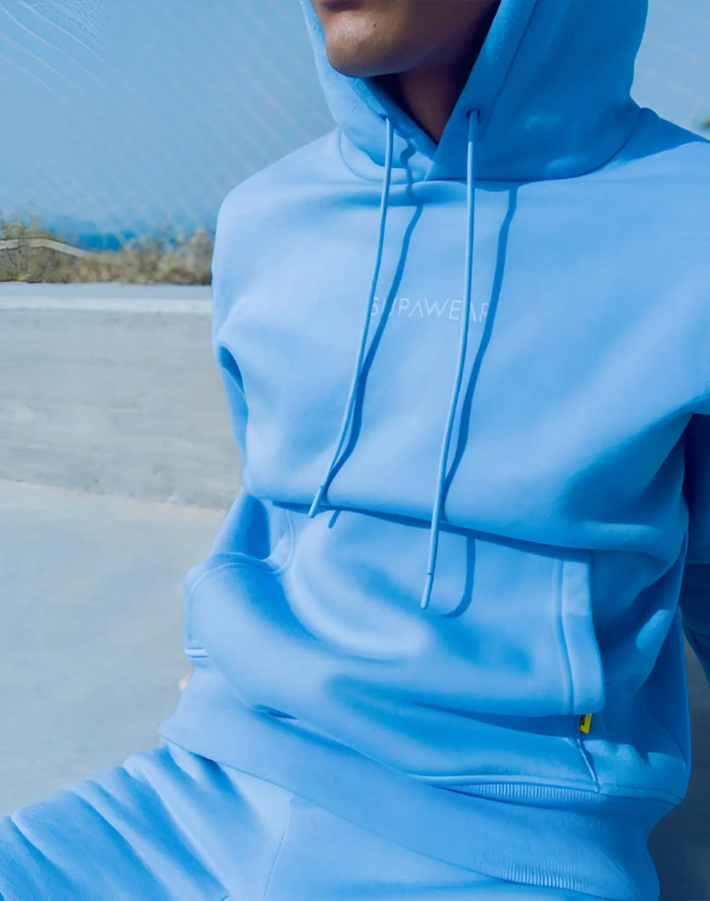 Light blue SUPAWEAR recovery hoodie with subtle white chest embroidery and matching drawstrings for comfort