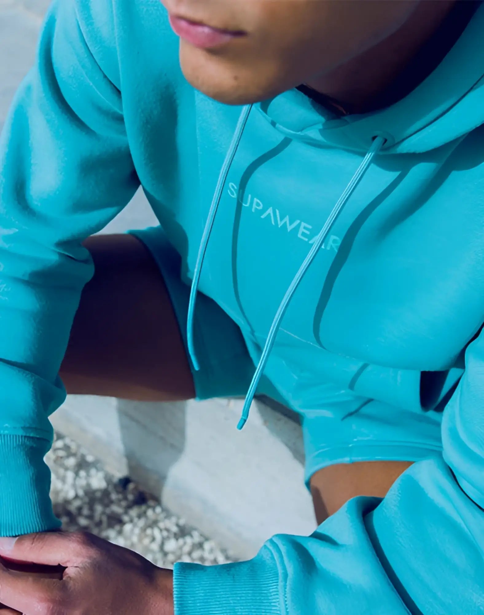 A vibrant turquoise supawear recovery hoodie with matching drawstrings and subtle embroidered logo on the chest