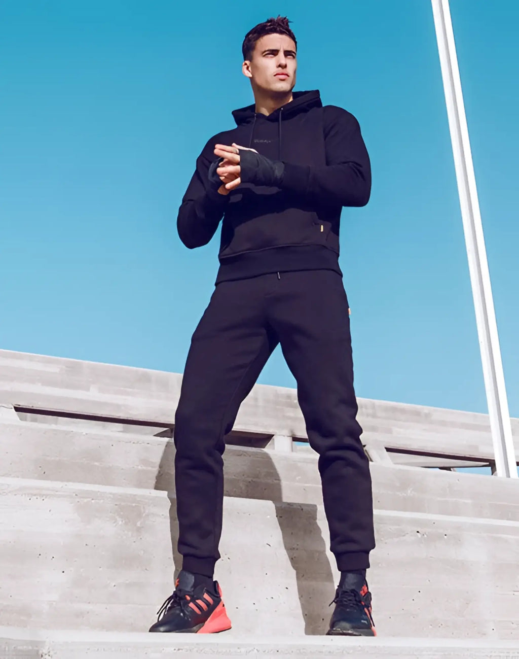 Black supawear recovery pants paired with a black athletic hoodie with subtle logo and black sneakers with orange accents