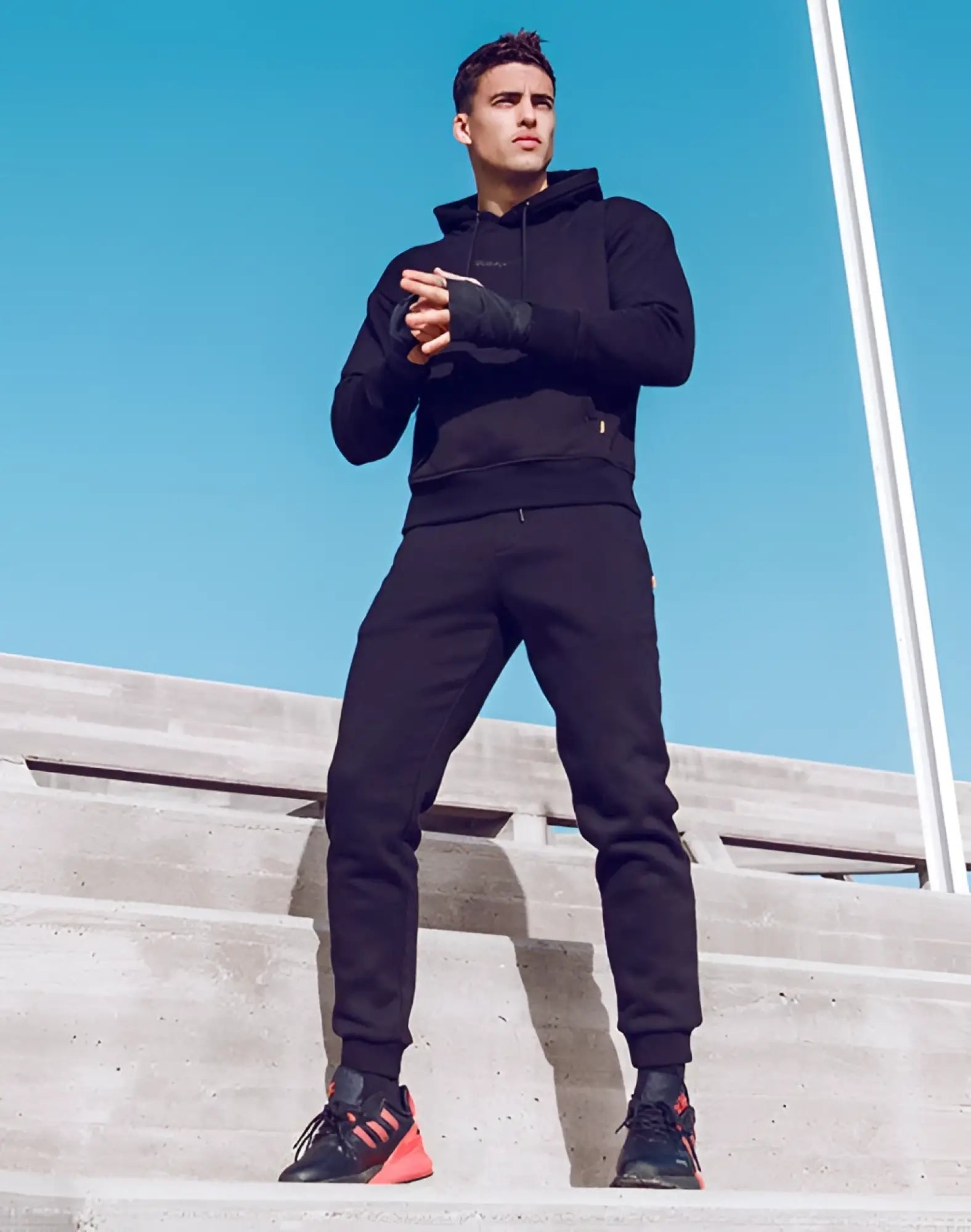 Black supawear recovery pants paired with a black athletic hoodie with subtle logo and black sneakers with orange accents