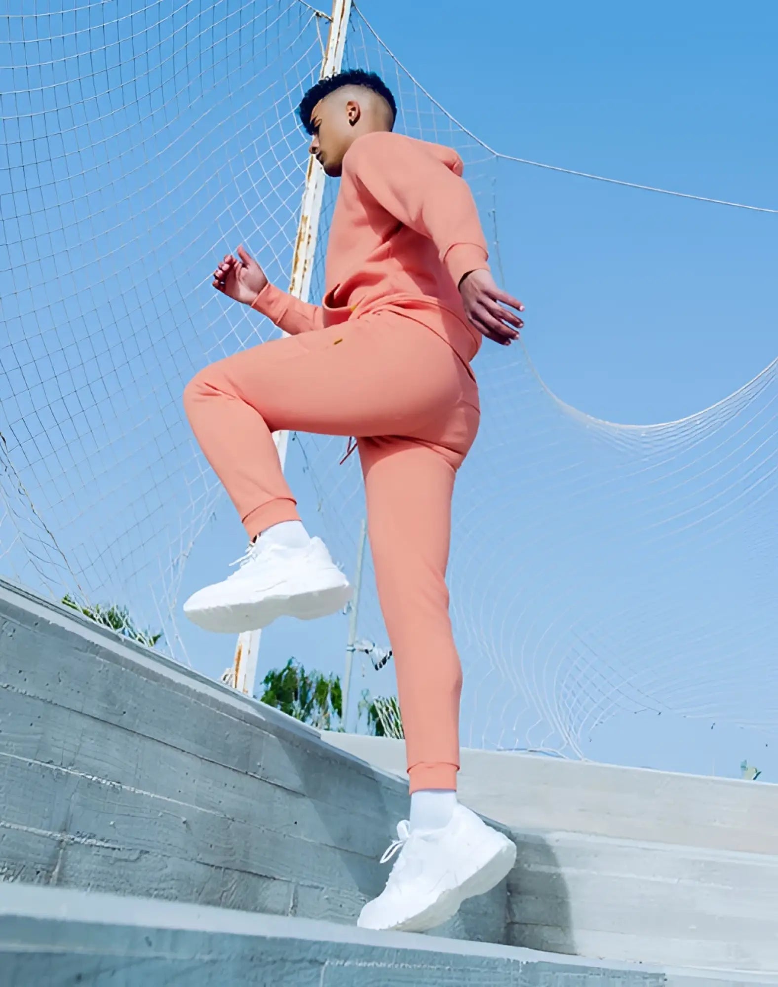 Coral-colored SUPAWEAR recovery pants and matching athletic sweatshirt set designed for comfortable activewear