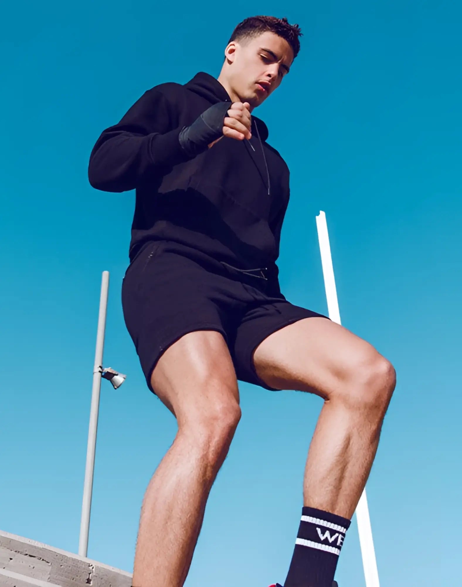 Black athletic hoodie with drawstring and ribbed cuffs paired with supawear recovery shorts in black shown from front
